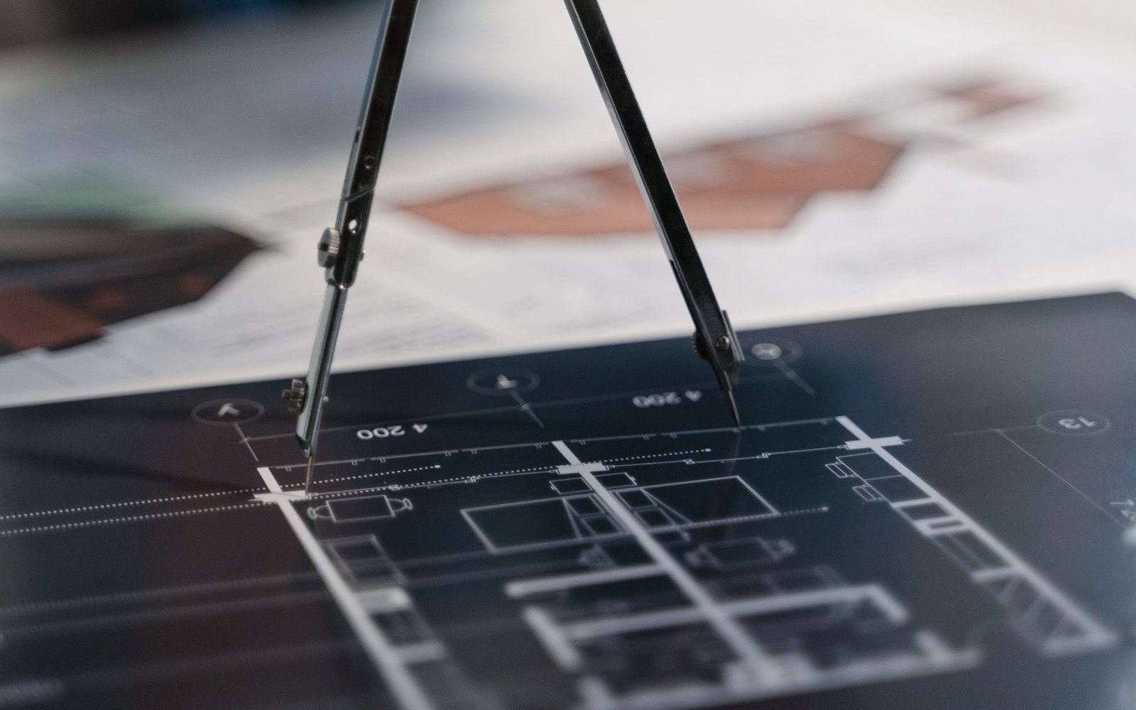 A drawing compass resting on an architectural blueprint