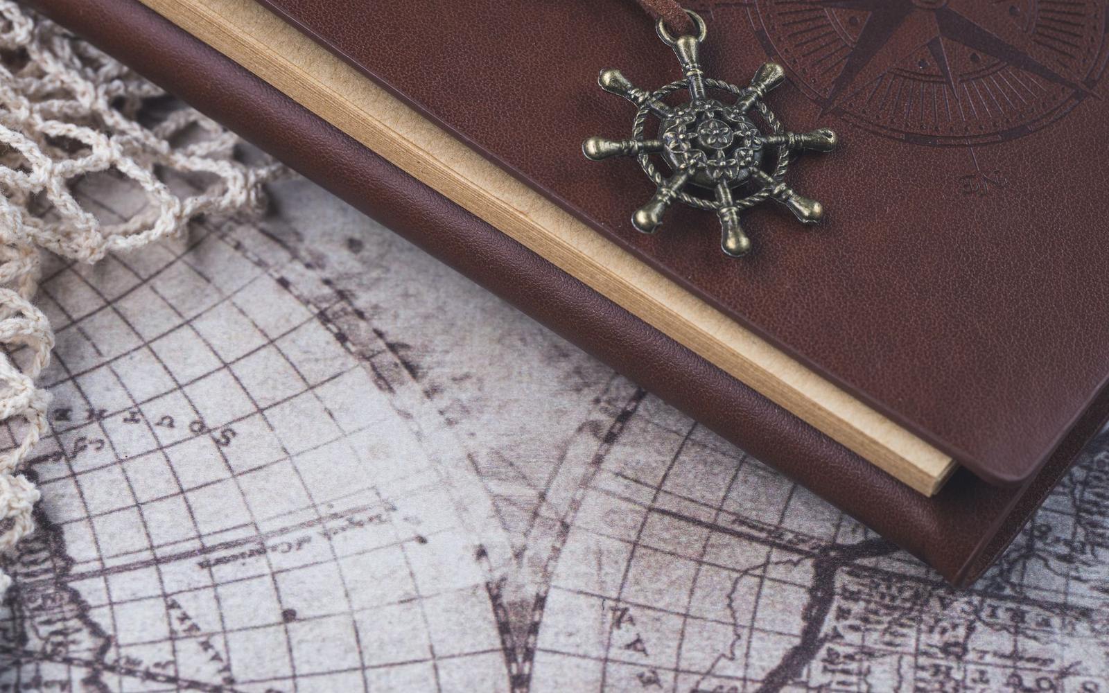 A leather-bound journal lying on an antique world map
